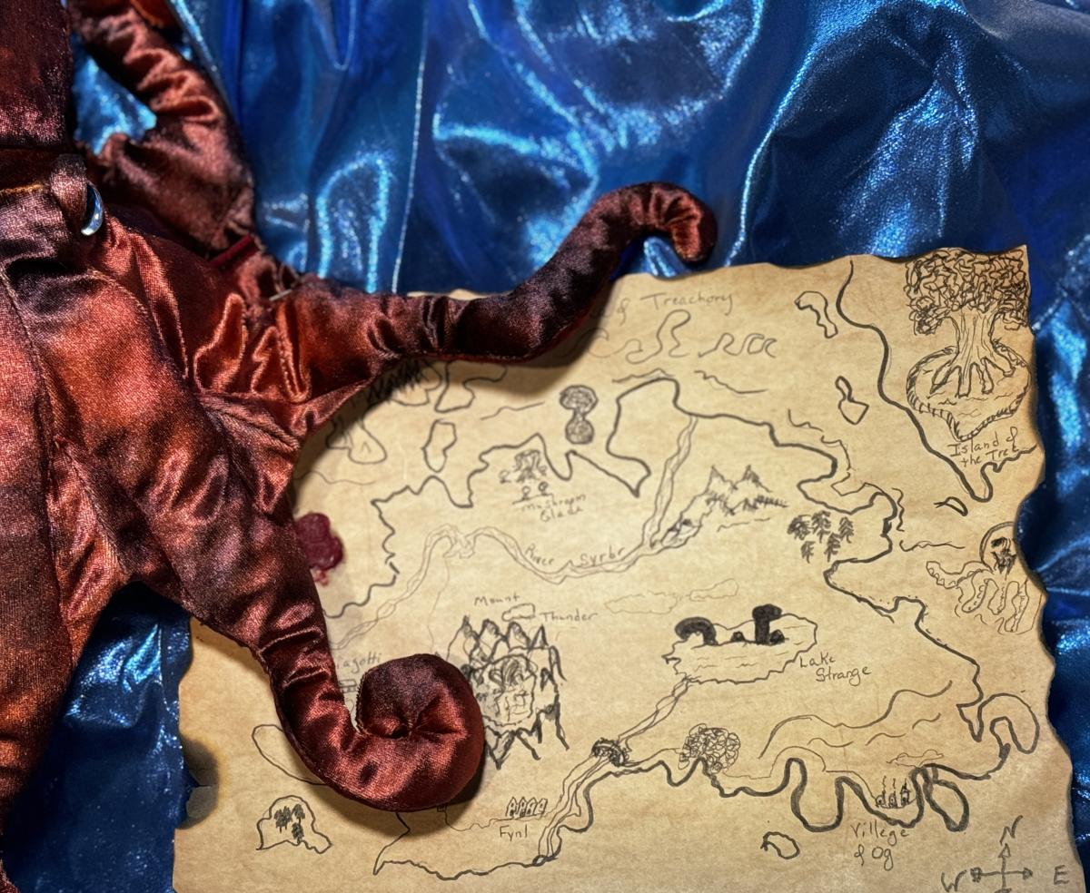 hand drawn map with red octopus on left sitting on a blue shiny fabric